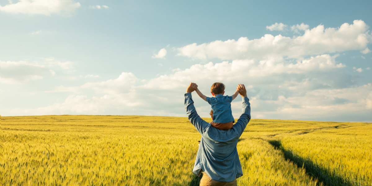 Father and son in field holding arms in the air